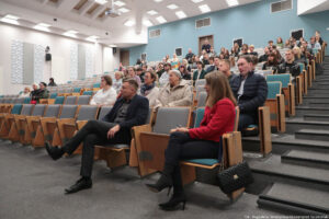 Sala wykładowa (ujęcie bokiem). Na krzesłach w ustawieniu stopniowym trzydziestu studentów i innych uczestników Dni Adaptacyjnych.