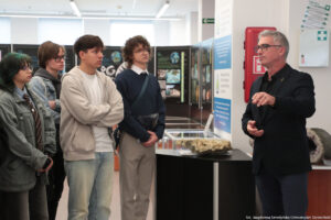 Muzeum Geologiczne. Po lewej czworo studentów. Po prawej dyrektor oprowadzający uczestników Dni Adaptacyjnych. W tle plansze informacyjne i gabloty z eksponatami.