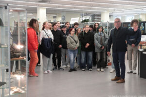 Muzeum Geologiczne. Po lewej przeszklona wysoka gablota z podświetlonymi eksponatami. W środku około 20-osoba grupa studentów. Po prawej dyrektor oprowadzający uczestników Dni Adaptacyjnych.
