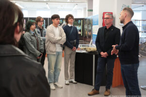 Muzeum Geologiczne. Po lewej czworo studentów. Po prawej dyrektor oprowadzający uczestników Dni Adaptacyjnych. W tle plansze informacyjne i gabloty z eksponatami.