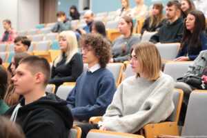 Sala wykładowa (ujęcie bokiem). Na krzesłach w ustawieniu stopniowym kilkunastu studentów – uczestników Dni Adaptacyjnych.
