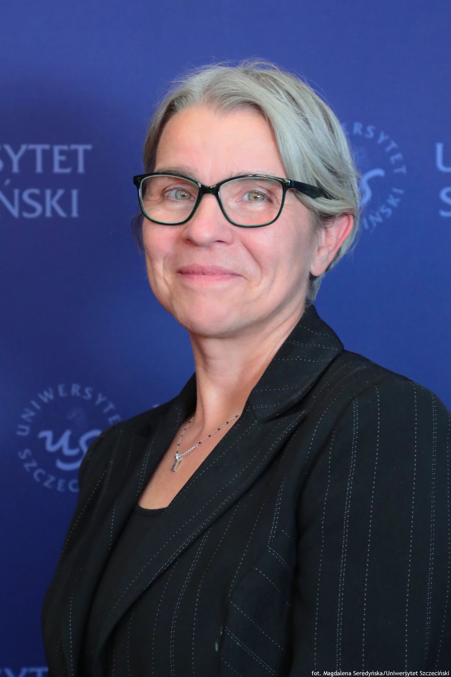 Portret kobiety. W tle granatowa ścianka US. Ujęcie do piersi.