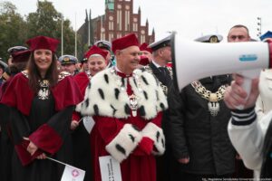 Spacerek na uniwerek. W środku rektorzy Uniwersytetu Szczecińskiego ubrany w czerwoną togi z gronostajami stoją z przedstawicielami szczecińskich uczelni. W tle kościół św. św. Piotra i Pawła.