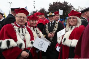 Na pierwszym planie prorektorzy Uniwersytetu Szczecińskiego w czerwonych togach z gronostajami. W środku przedstawicielka Politechniki Morskiej w mundurze. W tle przedstawiciele innych uczelni w togach i mundurach.