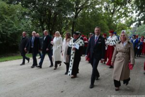 Spacerek na uniwerek. Park – w tle drzewa. W pierwszym rzędzie oficjele. Za nimi przedstawiciele szczecińskich uczelni ubrani w uroczyste togi z gronostajami.