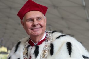 Jasne tło. Ujęcie do piersi. Na zdjęciu rektor Uniwersytetu Szczecińskiego w czerwonej todze z gronostajami.