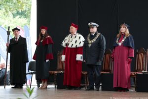 Inauguracja roku akademickiego. Scena. Na niej rektorzy szczecińskich uczelni w uroczystych togach. Za nimi krzesła. Po lewej pedel w czarnej todze.