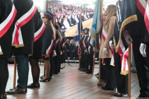 Ujęcie bokiem. Stojące w dwóch rzędach poczty sztandarowe.