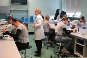 Noc Biologów 2026. Sala laboratoryjna i osoby obserwujące preparaty pod mikroskopami.