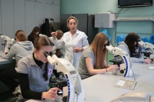 Noc Biologów 2026. Sala laboratoryjna i osoby obserwujące preparaty pod mikroskopami.
