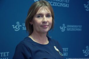 Laureatka Orderu Uśmiechu 2025 (ujęcie do piersi). Tło granatowe z niebieskimi logami Uniwersytetu Szczecińskiego.
