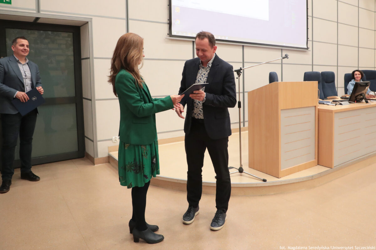 Perły Instytutu Ekonomii i Finansów 2025. Po prawej wyróżniony naukowiec odbierający teczkę, po lewej dyrektorka Instytutu.