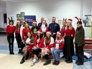 zdjęcie przedstawiają grupę ludi ubranych na czerwono oraz w mikołajkowe stroje, którzy pozują do zdjęcia wraz z dwoma funkcjonariuszami policji